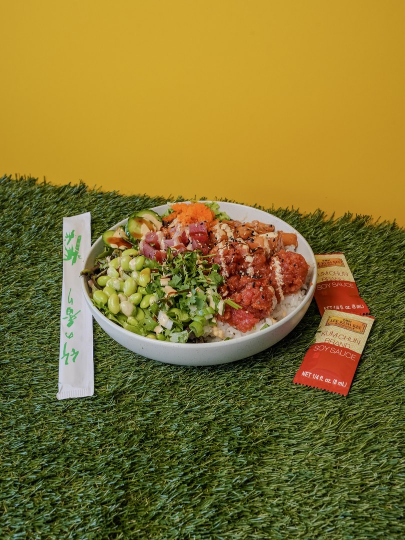 Pokitomik poke bowl on turf against a yellow wall